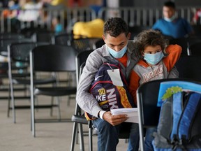 A Honduran seeking asylum and his daughter, 4, wait to be called to get tested for COVID-19 at the bus station in Brownsville, Texas, Monday, March 15, 2021.