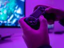 Close-up of an anonymous man's hands holding a modern controller while playing a video game in a dark room