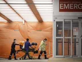 Paramedics wheel a patient into the emergency department at Mount Sinai Hospital in Toronto, Wednesday, Jan. 13, 2021.