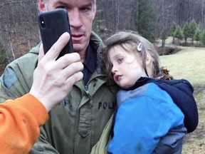 Ontario Provincial Police Const. Scott McNames carries Jude Leyton, 3, back to his family in South Frontenac while FaceTiming his parents on Wednesday. Jude had been missing in the thick forest for three and a half days.