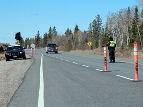 A Kenora OPP officer directs traffic entering Ontario at the rest stop at the provinical border with Manitoba on Monday, April 19. The Ontario government has placed restrictions on inter-provincial travel amid rising COVID-19 cases.