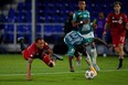 Toronto FC's Nick DeLeon and Leon defender Jaine Barreiro get tripped up battling for the ball.