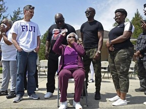 Jessie Hamilton, seated, reacts as several Louisiana State University members of Phi Gamma Delta, commonly called Fiji, surprise her with $51,765 to pay off her mortgage. Hamilton, 74, worked as a cook at the Fiji fraternity house for 14 years.