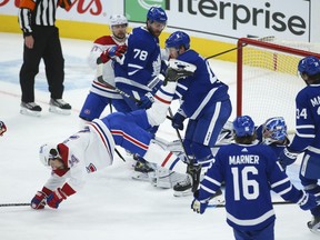 Montreal Canadiens' Phillip Danault is flattened by Maple Leafs' Morgan Rielly after slamming into goalie Jack Campbell during a scramble in front of the net during the third period in Toronto on Wednesday, April 7, 2021.