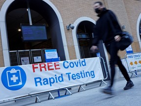 A pedestrian wearing a face covering walks past a sign directing people to a rapid lateral flow COVID-19 testing centre at London Bridge train station in central London on April 5, 2021.