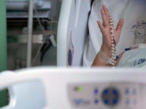 A Brazilian COVID-19 patient holds up a rosary in a hospital in Belem, Brazil in April, 2021.