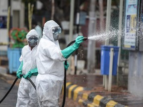 Members from the Disaster Response Force (DRF) of Telangana State, wearing protective gear spray disinfectant on a street against the spread of the Covid-19 coronavirus in Hyderabad on April 19, 2021.
