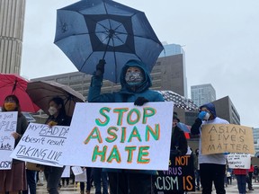 People hold placards as they gather to protest against anti-Asian hate crimes, racism and vandalism, outside City Hall in Toronto in March.