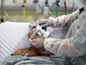 A physiotherapist adjusts an oxygen mask on a patient with COVID-19 at the ICU of Parelheiros Municipal Hospital in Sao Paulo, Brazil, April 8, 2021.