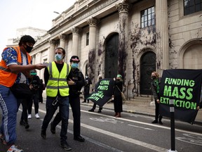 A police officer detains an activist from the Extinction Rebellion, a global environmental movement, during a protest outside the Bank of England building, in London, Britain, April 1, 2021.