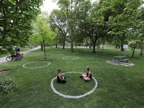 Women sit in a field where circles were painted to help visitors maintain social distancing to slow the spread of the coronavirus disease (COVID-19) at Trinity Bellwoods park in Toronto, Ontario, Canada May 28, 2020.