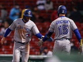 Blue Jays third baseman Cavan Biggio (left) celebrates scoring a run with Randal Grichuk against the Red Sox during the first inning at Fenway Park in Boston, Wednesday, April 21, 2021.
