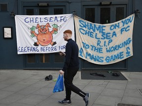 A Chelsea fan walks past banners outside the stadium after reports suggest they are set to pull out of the European Super League.