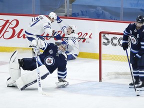 Mitch Marner celebrates with linemate Nick Foligno his gift first-period goal against Jets goaltender Connor Hellebuyck  in Winnipeg on Saturday, April 24, 2021.