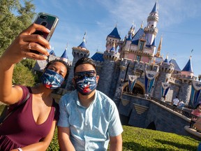 In this handout photo provided by Disneyland Resort, guests pose in front of Sleeping Beauty Castle at the Disneyland Resort on April 30, 2021 in Anaheim, Calif.