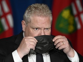 Ontario Premier Doug Ford puts his mask on after speaking at a press conference at Queen's Park, in Toronto, Friday, April 16, 2021.