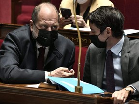 French Justice Minister Eric Dupond-Moretti (left) speaks with French Government spokesperson Gabriel Attal during a session of questions to the government at the National Assembly in Paris, Tuesday, April 13, 2021.