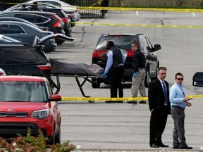 Officials load a body into a vehicle at the site of a mass shooting at a FedEx facility in Indianapolis, Indiana, Friday, April 16, 2021.