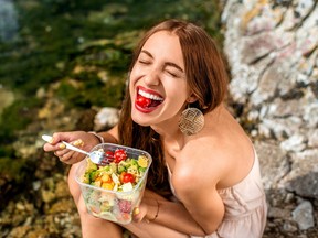 Woman eating healthy salad near the river