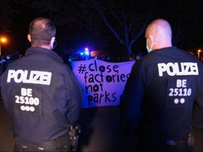 Police officers stand guard as demonstrators protest against a curfew set to curb the spread of COVID-19 in Berlin, Germany, Wednesday, April 28, 2021.