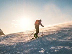 Man skier with backpack trekking on snow mountain with sunlight and storm.