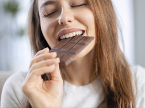 Cheerful young woman eating chocolate at home.