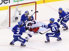 Riley Nash of the Columbus Blue Jackets battles for the loose puck with Justin Holl and Pierre Engvall of the Toronto Maple Leafs during their playoff series last August. Nash was traded to the Leafs on Friday.