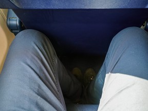 Looking down at narrow leg space in low cost airline seat, knees touching back rest at front.