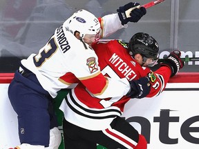 Vinnie Hinostroza (13) of the Florida Panthers collides with Ian Mitchell of the Chicago Blackhawks at the United Center on March 25, 2021 in Chicago.