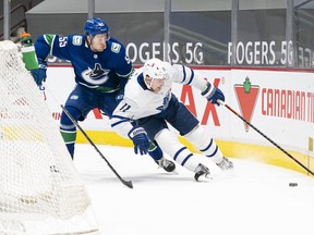 Canucks' Guillaume Brisebois tries to check Maple Leafs' Zach Hyman off the puck at Rogers Arena in Vancouver on Sunday, April 18, 2021.