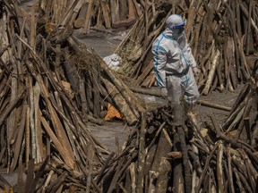 A man wearing PPE kit can be seen amid funeral pyres before they were lit to perform the last rites of the patients who died of the coronavirus disease at a crematorium on April 24, 2021 in New Delhi, India.