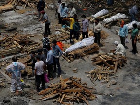 People prepare funeral pyres for COVID-19 victims during a mass cremation at a crematorium in New Delhi, India, Monday, April 26, 2021.
