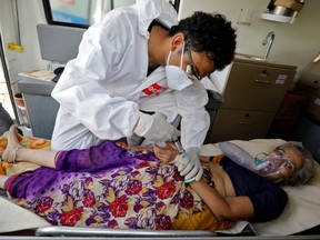 A doctor tends to a patient with a breathing problem inside an ambulance waiting to enter a COVID-19 hospital for treatment, in Ahmedabad, India, Sunday, April 25, 2021.