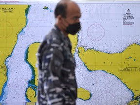 A member of the Indonesian Navy walks past a map of the search area for the submarine KRI Nanggala-402 at I Gusti Ngurah Rai airport in Bali, Indonesia, April 23, 2021.