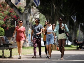 Pedestrians walk on a boulevard as Israel rescinds the mandatory wearing of face masks outdoors in the latest return to relative normality, boosted by a mass-vaccination campaign against the COVID-19 pandemic, in Tel Aviv, Israel April 18, 2021.