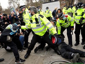 Police officers restrain demonstrators during a protest in London, Britain, April 3, 2021.