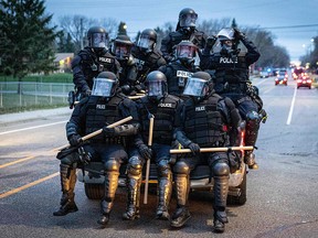Minneapolis police officers in riot gear leave as protesters gather after an officer shot and killed a man in Brooklyn Center, Minneapolis, Minnesota on April 11, 2021.