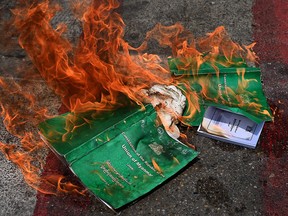 Copies of the 2008 constitution are burnt during a demonstration by protesters against the military coup in Yangon's South Okkalapa township on April 1, 2021.
