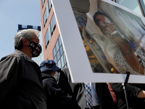 Baozhen Chen stands behind a photo of her husband Yao Pan Ma in critical condition at a hospital, after being assaulted on April 23 in Harlem, during a press conference in New York April 27, 2021.