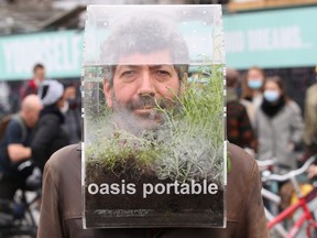 Belgian artist Alain Verschueren wears his "Portable Oasis" while performing in a street, saying he wanted to be in his bubble in the middle of the city, amid the COVID-19 outbreak in Brussels, Belgium, April 16, 2021.