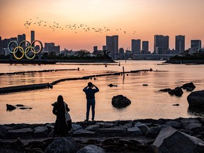 People gathered as the Olympic rings are lit at the waterfront of Odaiba in Tokyo on April 20, 2021.
