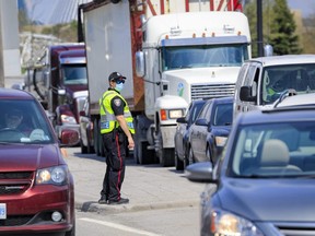 An Ottawa Police Service officer monitors traffic on King Edward Avenue in Ottawa after crossing into Ontario from Quebec via the on the Macdonald-Cartier Bridge, Monday, April 19, 2021.