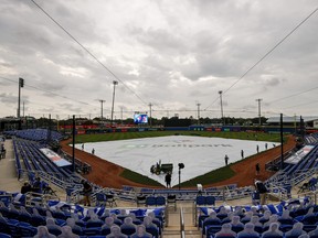 A general view of the grounds crew laying the tarp down on the field in anticipation of approaching inclement weather prior to the game between the Blue Jays and the Los Angeles Angels  at TD Ballpark on April 10, 2021 in Dunedin, Fla.