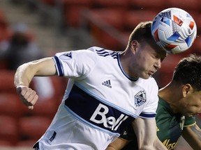 Vancouver Whitecaps FC midfielder Andy Rose (left) heads the ball during his team's game against the Portland Timbers on April 18, 2021.