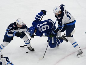 Winnipeg Jets' Neal Pionk (left) and Adam Lowry (right) check Maple Leafs' John Tavares during the first period at Scotiabank Arena in Toronto on Thursday, April 15, 2021.