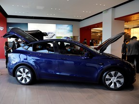 Visitors wearing masks check a China-made Tesla Model Y sport utility vehicle (SUV) at the electric vehicle maker's showroom in Beijing January 5, 2021.