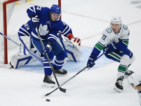 Maple Leafs' Travis Dermott keeps the puck away from Vancouver Canucks' Travis Boyd during the second period in Toronto on Thursday, April 29, 2021.