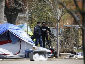 A Toronto Fire Prevention officer, Toronto Police and electricians from Black and McDonald were on hand at the south end of the tent city in Alexandra Park after discovering electrical wiring from a park lamp post was feeding electricity inside part of a large white tent encampment on Tuesday, April 27, 2021.