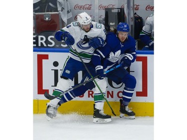 Vancouver Canucks J.T. Miller C (9) takes out Toronto Maple Leafs Justin Holl (3) along the boards during the first period in Toronto on Thursday April 29, 2021. Jack Boland/Toronto Sun/Postmedia Network