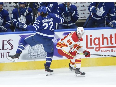 Calgary Flames Andrew Mangiapane LW (88)ducks a check from Toronto Maple Leafs Zach Bogosian D (22) during the second period in Toronto on Tuesday April 13, 2021. Jack Boland/Toronto Sun/Postmedia Network